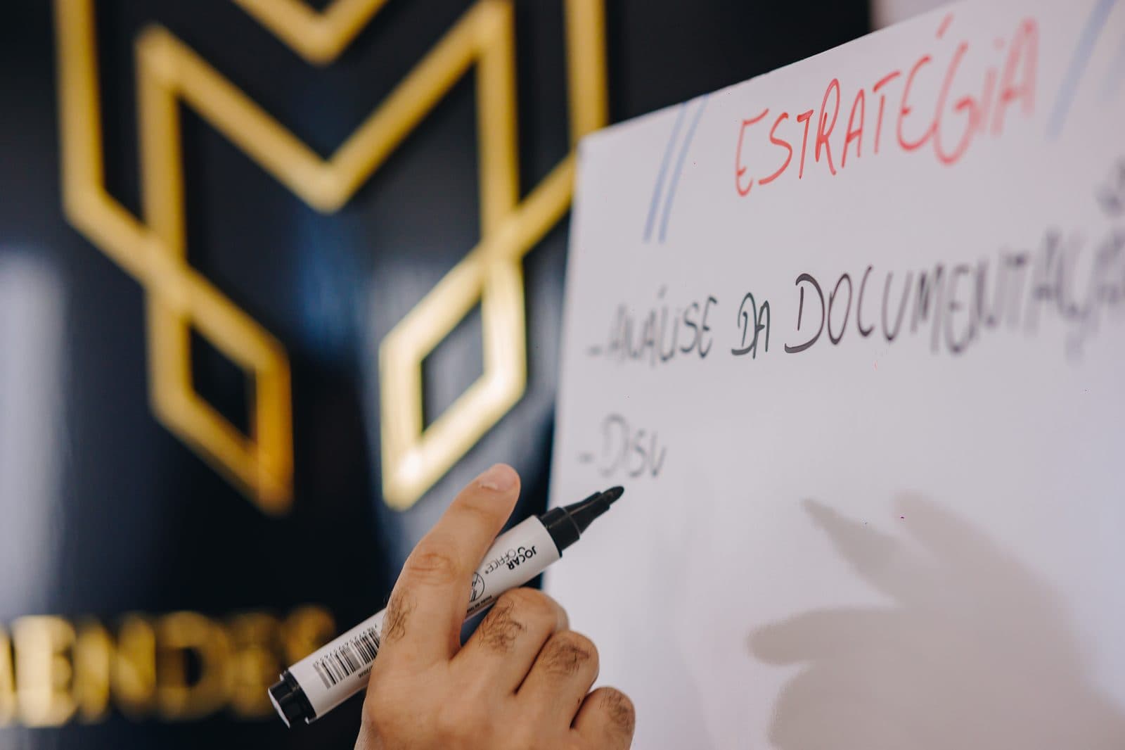 Advogado anotando a estratégia de um caso diante do logotipo do escritório